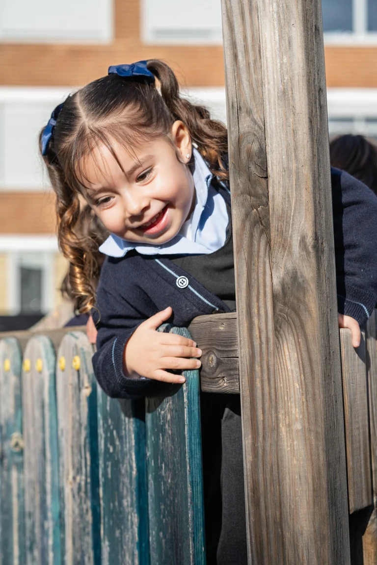 Little girl climbing over a railing 