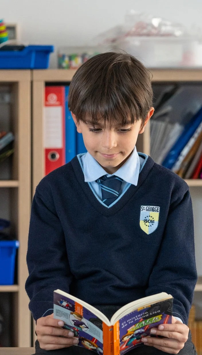Student in uniform reading a book