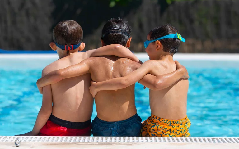 Three students hugging during swim lesson