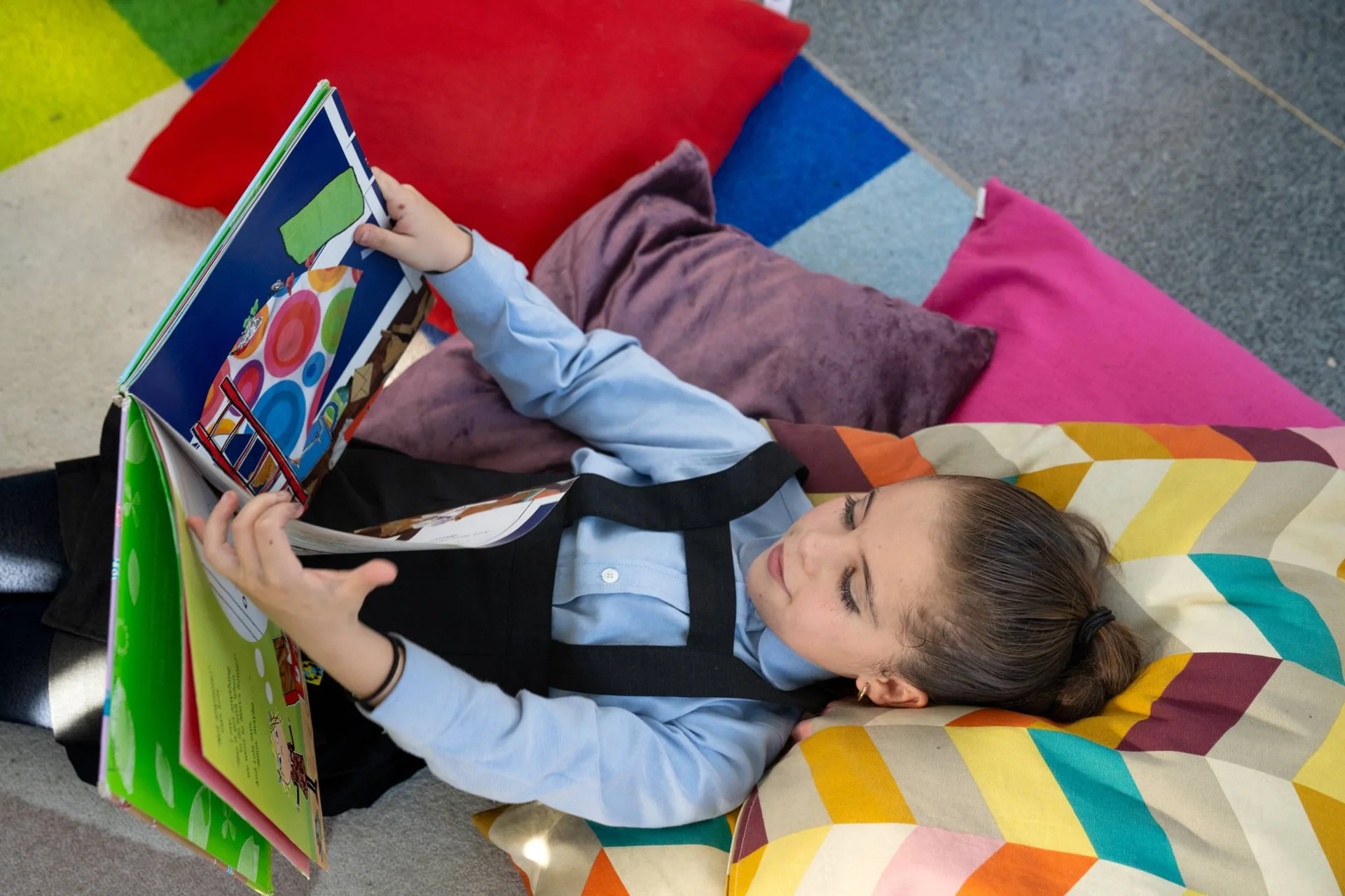 Little student reading a book on a couch