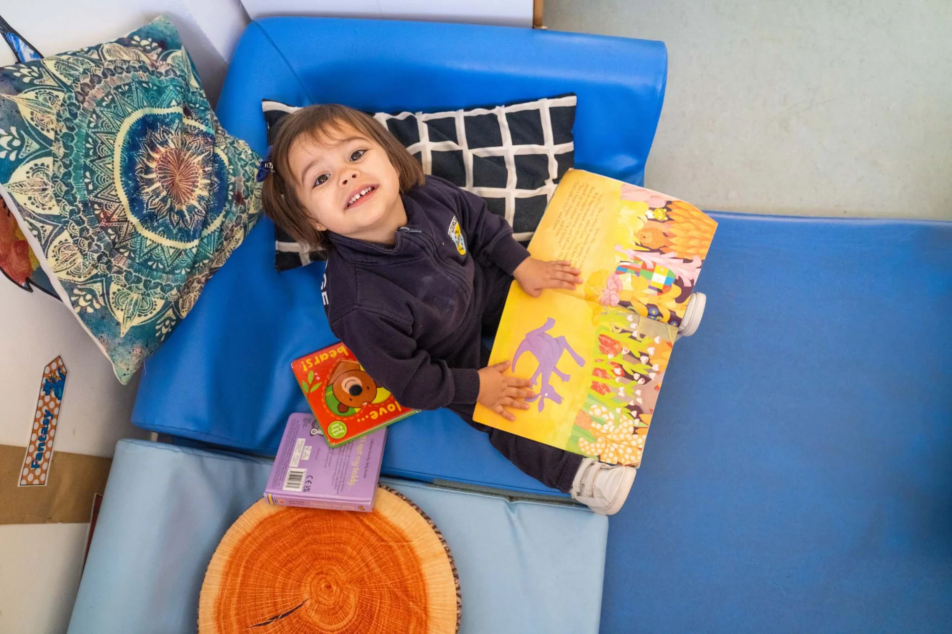 Little girl smiling with a book on her legs