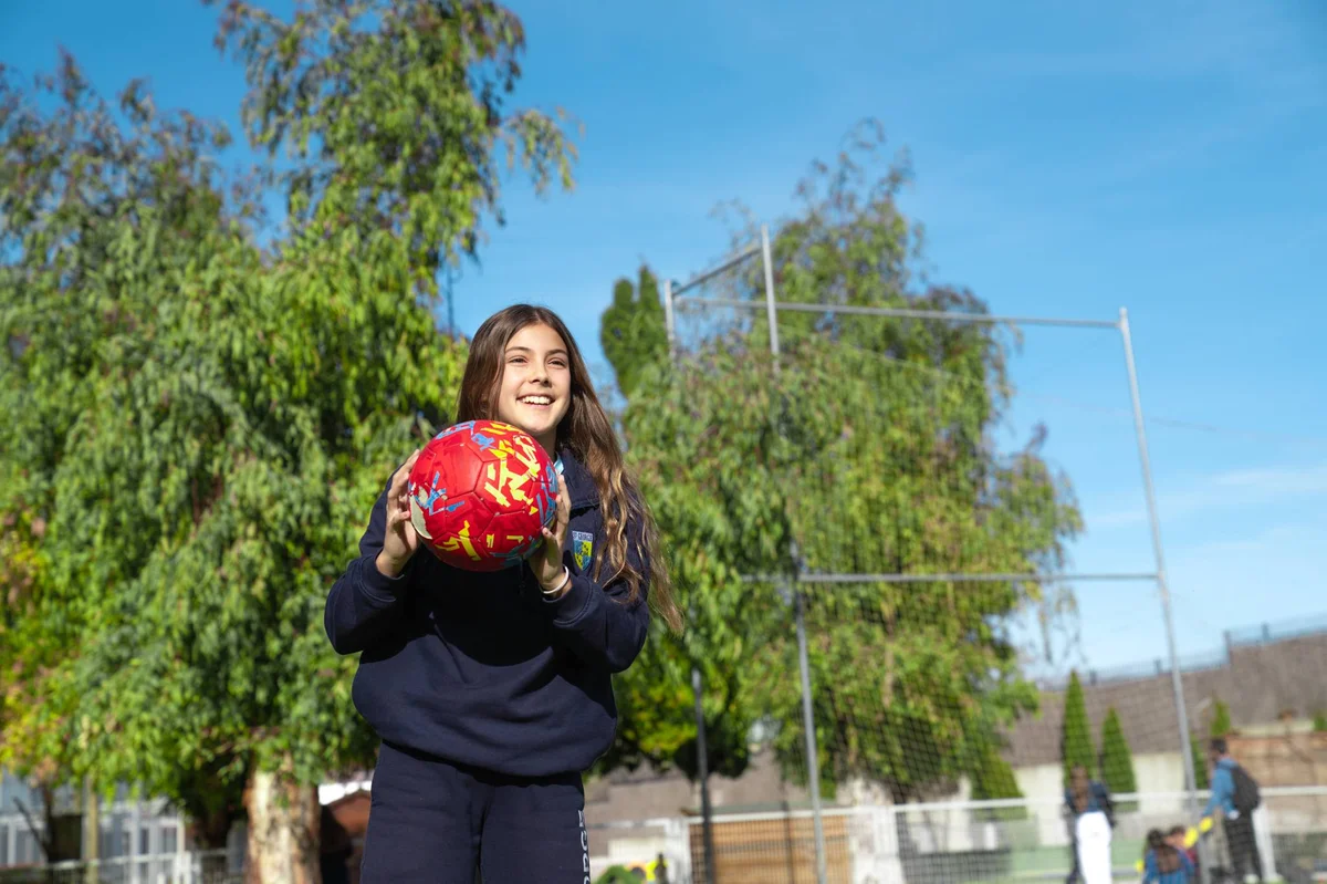 Student holding a ball and smiling
