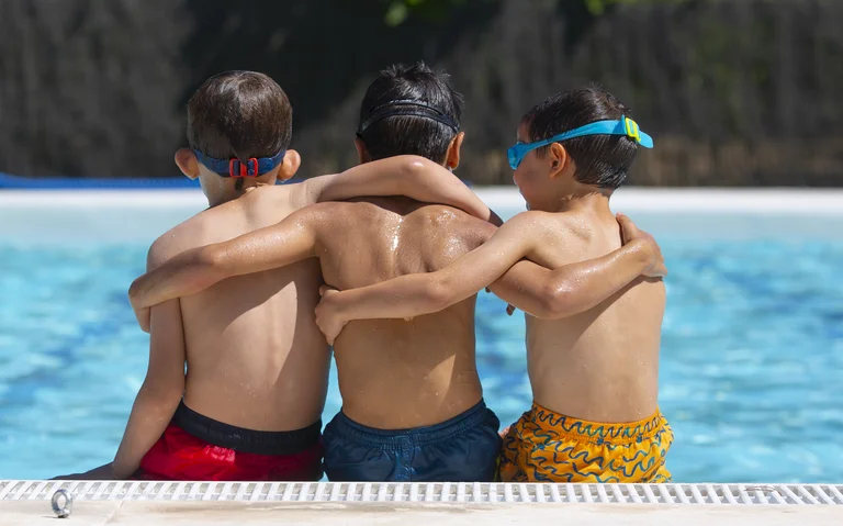 Three students hugging during swim lesson